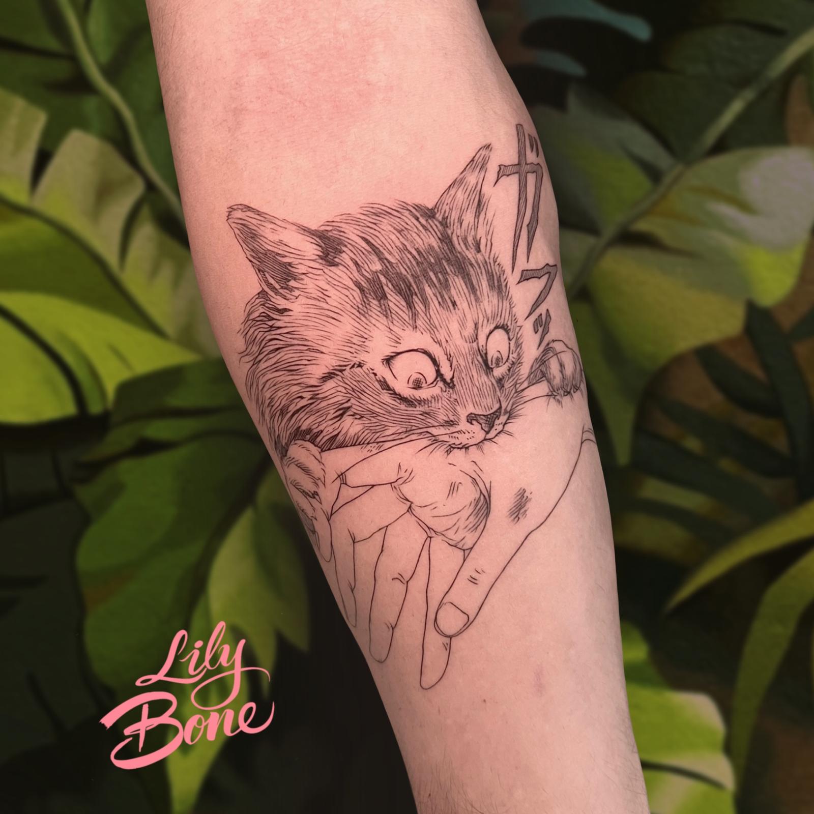 Imagen en primer plano de un tatuaje de línea fina en el brazo de un hombre que muestra a un gato mordiendo una mano.